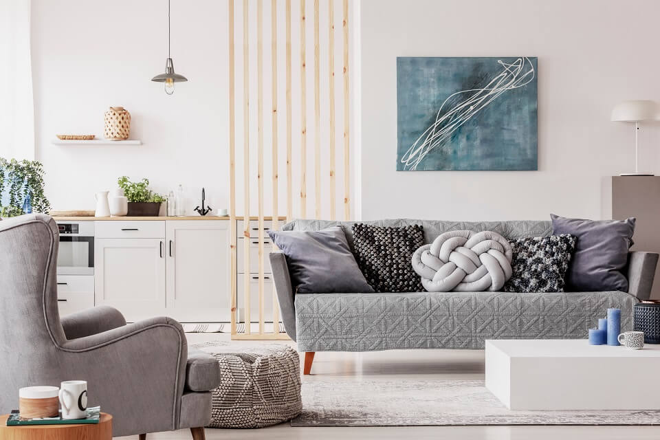 Living room with sofas and cushions in gray and behind it a white kitchen