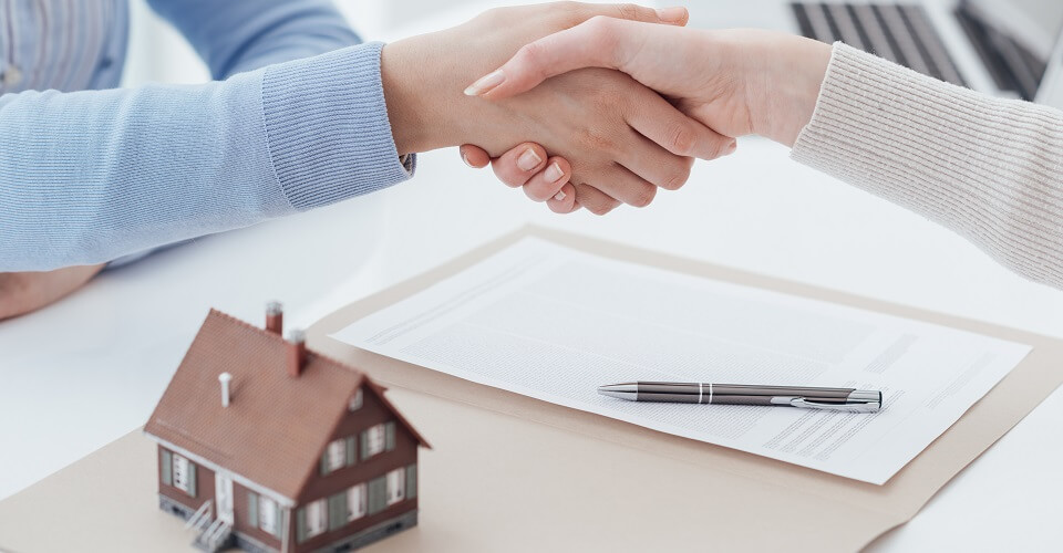 Handshake and next to a model of a house